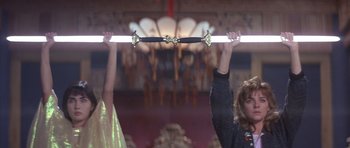 Movie still from “Big Trouble in Little China” (1986), directed by John Carpenter – Two people holding onto a bar in a theater; Medium shot, Low angle