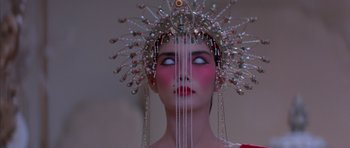Movie still from “Big Trouble in Little China” (1986), directed by John Carpenter – A woman wearing a headdress and a red dress; Close Up shot, Low angle