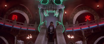 Movie still from “Big Trouble in Little China” (1986), directed by John Carpenter – A man in a costume standing on a stair case; Wide shot, Low angle
