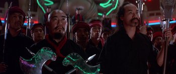 Movie still from “Big Trouble in Little China” (1986), directed by John Carpenter – A group of men standing next to each other in a room; Medium shot, Low angle