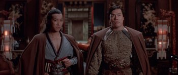 Movie still from “Big Trouble in Little China” (1986), directed by John Carpenter – Two asian men standing next to each other in a room; Medium shot, Low angle