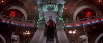 Movie still from “Big Trouble in Little China” (1986), directed by John Carpenter – A statue of a man with a crown on top of an escalator; Wide shot, Low angle