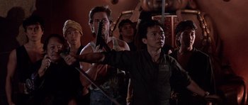 Movie still from “Big Trouble in Little China” (1986), directed by John Carpenter – A group of people standing in front of a wall; Medium shot, Low angle