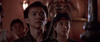 Movie still from “Big Trouble in Little China” (1986), directed by John Carpenter – Two asian men standing next to each other in front of a statue; Close Up shot, Low angle
