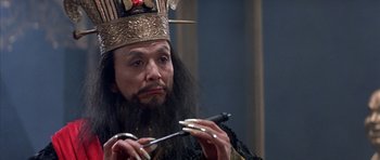 Movie still from “Big Trouble in Little China” (1986), directed by John Carpenter – A man in a crown holding a pair of scissors; Close Up shot, High angle