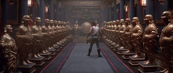 Movie still from “Big Trouble in Little China” (1986), directed by John Carpenter – A man is standing in front of a row of gold statues; Wide shot, High angle