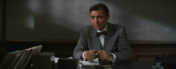 Movie still from “Bigger Than Life” (1956), directed by Nicholas Ray – A man in a suit sitting at a table; Medium shot, Over the shoulder angle