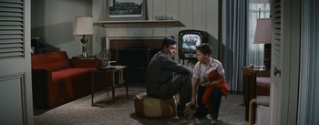 Movie still from “Bigger Than Life” (1956), directed by Nicholas Ray – A man and a boy sitting in a living room next to each other; Wide shot, Over the shoulder angle