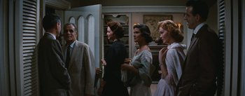 Movie still from “Bigger Than Life” (1956), directed by Nicholas Ray – A group of women standing next to each other in a room; Medium shot, Low angle