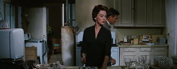 Movie still from “Bigger Than Life” (1956), directed by Nicholas Ray – A woman in a black dress standing in a kitchen; Medium shot, Low angle