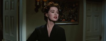 Movie still from “Bigger Than Life” (1956), directed by Nicholas Ray – A woman in a black dress and a black jacket; Close Up shot, Low angle