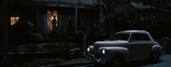 Movie still from “Bigger Than Life” (1956), directed by Nicholas Ray – A young boy standing in front of an older car; Extreme Wide shot, High angle