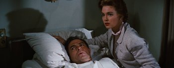 Movie still from “Bigger Than Life” (1956), directed by Nicholas Ray – A man laying in a hospital bed next to a woman; Close Up shot, Over the shoulder angle