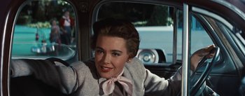 Movie still from “Bigger Than Life” (1956), directed by Nicholas Ray – A woman sitting in the back seat of a car; Close Up shot, Over the shoulder angle