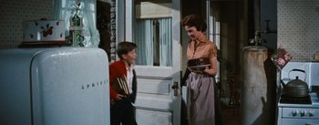 Movie still from “Bigger Than Life” (1956), directed by Nicholas Ray – A woman and a young boy standing in front of a door; Medium shot, Low angle