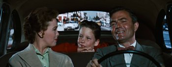 Movie still from “Bigger Than Life” (1956), directed by Nicholas Ray – A man and a woman and a child in a car; Medium shot, Over the shoulder angle