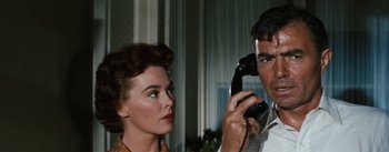 Movie still from “Bigger Than Life” (1956), directed by Nicholas Ray – A man and a woman looking at each other while holding a phone to their ear; Close Up shot, Low angle