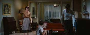 Movie still from “Bigger Than Life” (1956), directed by Nicholas Ray – Two people in a living room with a red couch; Wide shot, Over the shoulder angle
