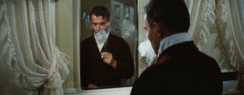 Movie still from “Bigger Than Life” (1956), directed by Nicholas Ray – A man smoking a pipe in front of a mirror; Medium shot, Over the shoulder angle
