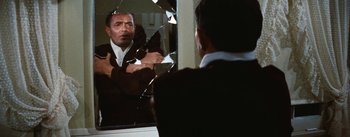 Movie still from “Bigger Than Life” (1956), directed by Nicholas Ray – A man looking at himself in a broken mirror; Medium shot, Over the shoulder angle