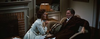 Movie still from “Bigger Than Life” (1956), directed by Nicholas Ray – An older woman sitting next to an older man in a chair; Medium shot, Over the shoulder angle