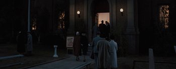 Movie still from “Bigger Than Life” (1956), directed by Nicholas Ray – A group of people standing in front of a building at night; Extreme Wide shot, High angle