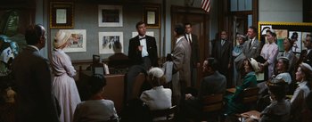 Movie still from “Bigger Than Life” (1956), directed by Nicholas Ray – A group of people sitting in a room talking to each other; Wide shot, High angle