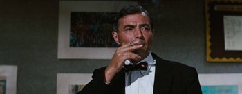 Movie still from “Bigger Than Life” (1956), directed by Nicholas Ray – A person wearing a suit smoking a cigarette; Close Up shot, Over the shoulder angle