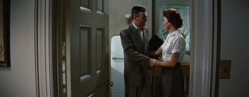 Movie still from “Bigger Than Life” (1956), directed by Nicholas Ray – A man and a woman shaking hands in a room; Medium shot, Over the shoulder angle