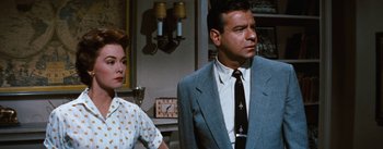 Movie still from “Bigger Than Life” (1956), directed by Nicholas Ray – A man and a woman standing next to each other in a room; Medium shot, Over the shoulder angle