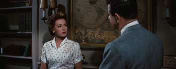 Movie still from “Bigger Than Life” (1956), directed by Nicholas Ray – A man and a woman are talking in front of a map; Medium shot, Over the shoulder angle