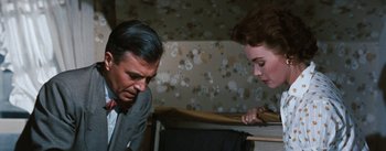 Movie still from “Bigger Than Life” (1956), directed by Nicholas Ray – A man and a woman looking at each other in a room; Medium shot, Over the shoulder angle