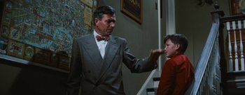 Movie still from “Bigger Than Life” (1956), directed by Nicholas Ray – An older man wearing a suit and bow tie talking to an older woman; Medium shot, Over the shoulder angle