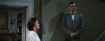 Movie still from “Bigger Than Life” (1956), directed by Nicholas Ray – A man and a woman are standing in front of a wall; Medium shot, Over the shoulder angle