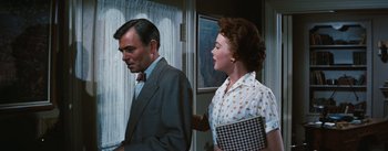 Movie still from “Bigger Than Life” (1956), directed by Nicholas Ray – A man and a woman standing next to each other in front of a window; Medium shot, Over the shoulder angle