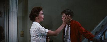 Movie still from “Bigger Than Life” (1956), directed by Nicholas Ray – A woman touching a boy's face with his hand; Medium shot, Over the shoulder angle