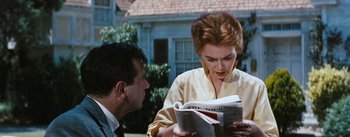 Movie still from “Bigger Than Life” (1956), directed by Nicholas Ray – A man and a woman looking at a book; Medium shot, Over the shoulder angle