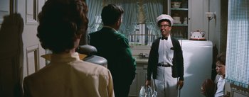 Movie still from “Bigger Than Life” (1956), directed by Nicholas Ray – A group of people standing in a kitchen; Medium shot, Over the shoulder angle