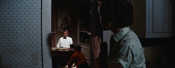 Movie still from “Bigger Than Life” (1956), directed by Nicholas Ray – A man sitting at a desk in front of a woman; Medium shot, Over the shoulder angle