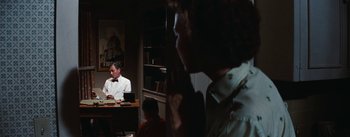 Movie still from “Bigger Than Life” (1956), directed by Nicholas Ray – A man sitting at a desk in front of a woman; Medium shot, Over the shoulder angle