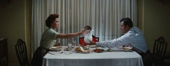 Movie still from “Bigger Than Life” (1956), directed by Nicholas Ray – A man and a woman at a dinner table with a pitcher of milk in front of them; Medium shot, High angle
