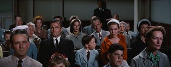 Movie still from “Bigger Than Life” (1956), directed by Nicholas Ray – A group of people sitting in front of each other in a courtroom; Medium shot, Low angle