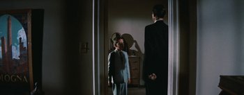 Movie still from “Bigger Than Life” (1956), directed by Nicholas Ray – A man in a suit and tie standing next to another man in a suit and tie; Medium shot, Over the shoulder angle