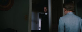 Movie still from “Bigger Than Life” (1956), directed by Nicholas Ray – A man in a suit and tie standing in a doorway; Medium shot, Over the shoulder angle