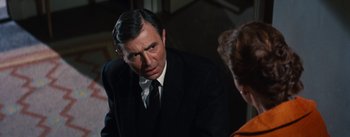 Movie still from “Bigger Than Life” (1956), directed by Nicholas Ray – A man in a suit and tie talking to a woman in a black suit; Close Up shot, Over the shoulder angle