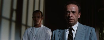 Movie still from “Bigger Than Life” (1956), directed by Nicholas Ray – A man in a white lab coat standing next to another man in a suit and tie; Close Up shot, Low angle
