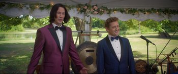 Movie still from “Bill & Ted Face the Music” (2020), directed by Dean Parisot – Two men standing next to each other in front of a tent; Medium shot, Over the shoulder angle