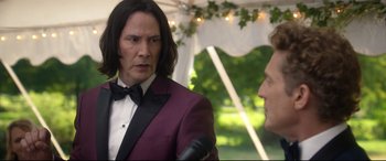 Movie still from “Bill & Ted Face the Music” (2020), directed by Dean Parisot – A man in a suit and bow tie talking to another man; Medium shot, Over the shoulder angle