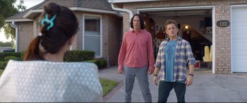 Movie still from “Bill & Ted Face the Music” (2020), directed by Dean Parisot – Two men standing in front of a woman in front of a house; Medium shot, Over the shoulder angle