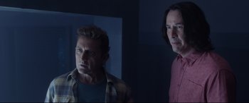 Movie still from “Bill & Ted Face the Music” (2020), directed by Dean Parisot – Two men standing next to each other in a dark room; Medium shot, Over the shoulder angle